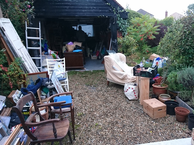 garage with rubbish stacked inside and on driveway